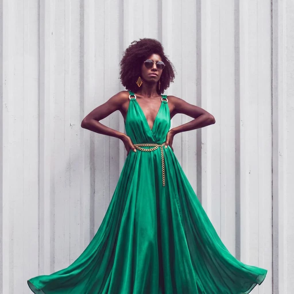 Have the model wear a vibrant emerald green silk maxi dress, flowing lightweight fabric with a subtle sheen, deep V-neckline, gold waist chain belt, high-end resort style, looking elegant and ethereal.